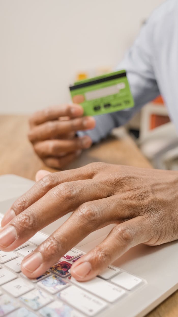 Close-up of hands using a credit card for online shopping on a laptop.